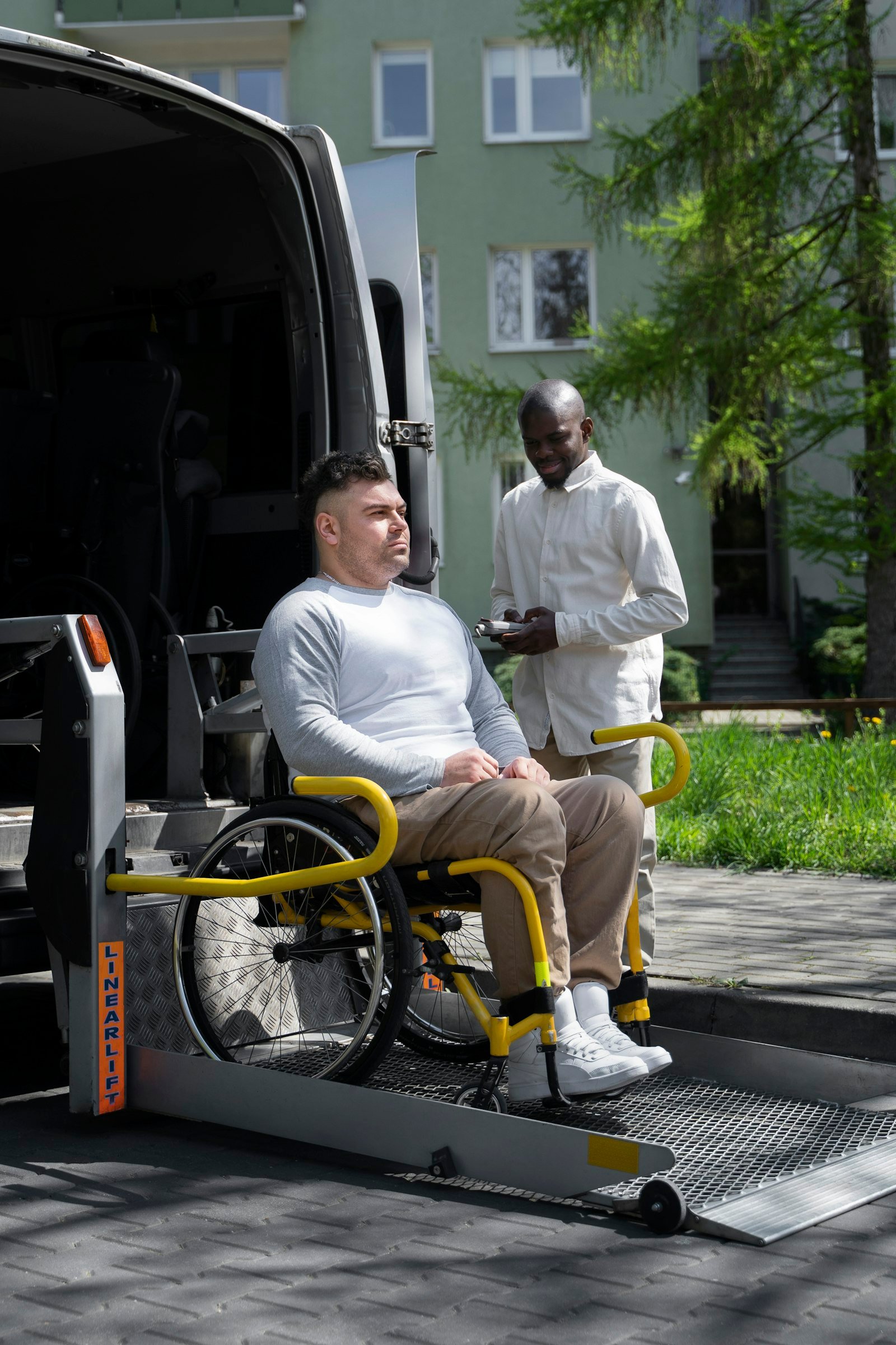 A driver assisting a passenger in a wheelchair on a van lift
